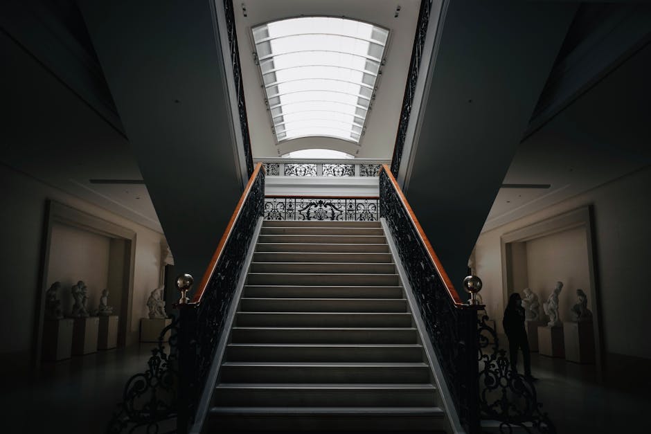 A dimly lit museum hallway with stairs and sculptures exuding an aura of artistic elegance.
